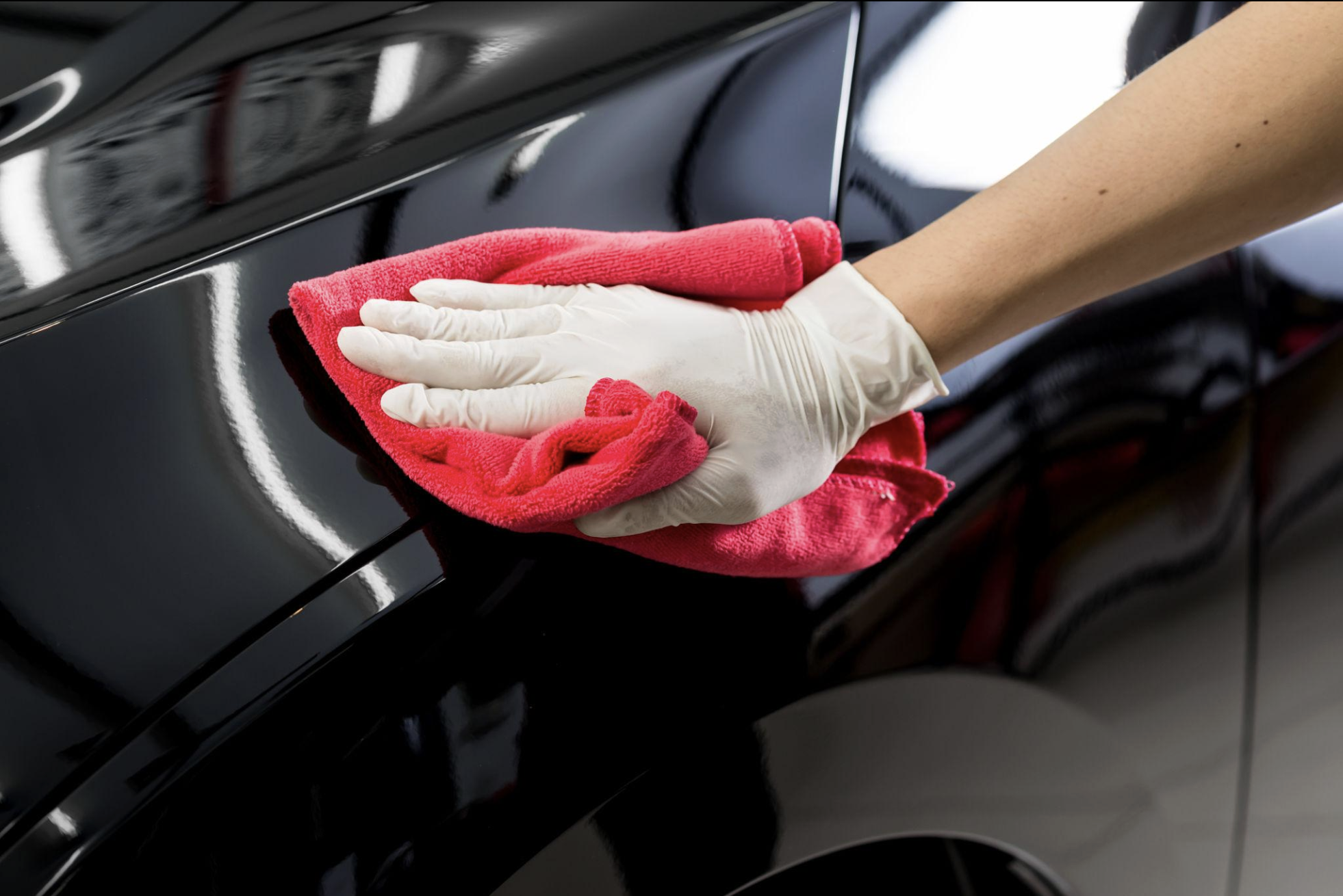 Hand polishing a glossy black car panel with a microfiber cloth